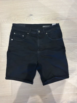 Dondup shorts - Snygga svarta jeansshorts med klassisk femficksdesign och uppvikta benslut. Shortsen har bälteshällor och knappgylf. Perfekta för en avslappnad stil och passar till det mesta.