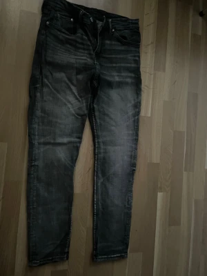 Mörkgrå slim fit jeans från HM, Storlek 32/32 - Säljer ett par svarta slim fit jeans med  tvättade detaljer. Jeansen har fem fickor, dragkedjegylf och smal passform. Perfekta för en trendig och avslappnad stil.