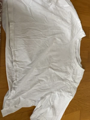 Vit croppad t-shirt i bomull - En enkel och stilren vit croppad t-shirt med rund hals och korta ärmar. Perfekt basplagg till alla outfits och tillverkad i mjuk bomull för skön känsla. Passar dig som gillar en clean och avslappnad look.