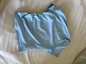 Ljusblå asymmetrisk t-shirt - En enkel och stilren ljusblå t-shirt i mjukt material. T-shirten har korta ärmar och en klassisk passform som passar till det mesta. Perfekt för dig som gillar en clean och fräsch look.
