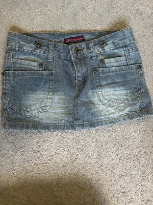  jeanskjol i S - Säljer en blå jeanskjol från Jin Jie Kang med slitna detaljer och fickor både fram och bak. Köpte i Stockholm på en secondhand butik men den är i jätte bra skick. Den passar bara inte mina höfter🥰