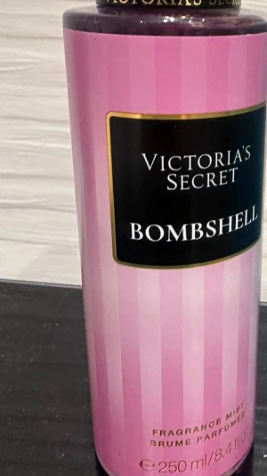 Victoria's Secret Bombshell mist - Fräsch och feminin body mist från Victoria's Secret i doften Bombshell. Flaskan är cylinderformad med rosa och ljusrosa ränder samt svart etikett med guldkant. Innehåller 250 ml och har en elegant design som känns lyxig och ungdomlig.