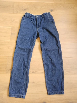 Blåa baggy jeans med resårmidja - Säljer ett par blå jeans med baggy passform och resår i midjan.. Stängs med knapp och dragkedja. Du kan knyta upp den vid midjan. Priset kan diskuteras