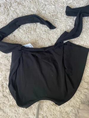 Svart tajt t-shirt med knyte i ryggen - Bilden är upp och ner vänd … men den är i jätte bra skick!