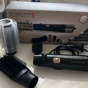 Remington varmluftsborste med tillbehör - Multifunktionell varmluftsborste från Remington med flera utbytbara borsthuvuden och stylingmunstycken. Borsten är svart och silver med rosa detaljer och tillverkad i plast och metall. Perfekt för att styla och torka håret samtidigt.