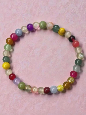 Färgglatt pärlarmband i glas - Ett armband med runda pärlor i olika färger som rött, grönt, gult, blått och lila. Pärlorna är gjorda av glas och har en glansig finish. Perfekt accessoar för att addera färg till din stil.