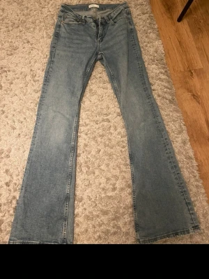 Blå bootcut jeans från Lee - Säljer ett par klassiska blå bootcut jeans från gina tricot, normal midja och är tillverkade i mjuk denim med lätt tvättad look. Perfekta för dig som gillar en avslappnad men ändå snygg stil.