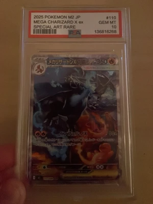Pokemon Mega Charizard X ex SAR JP - Obs ej orginal. Säljer ett samlarkort, 2025 Pokemon M2 JP Mega Charizard X ex Special Art Rare, graderat av PSA till GEM MT 10. Kortet har en cool illustration med Charizard i svart och blått med eldiga detaljer. Perfekt för dig som älskar Pokémon och vill ha något unikt i din samling.