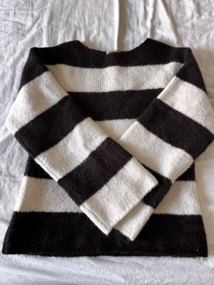 Randig stickad tröja från Gina Tricot - Säljer en fluffig stickad tröja från Gina Tricot i storlek XS. Tröjan har breda svarta och vita ränder, rund halsringning och långa ärmar. Perfekt för dig som gillar en avslappnad och trendig look. Pris går att diskutera💕
