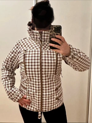 Burton Skid- & Snowboardjacka, stl L - Säljer en supersnygg och funktionell skidjacka från Burton i vitt med bruna detaljer och snyggt mönster. Jackan är i mycket bra skick (som ny).   Den har alla funktioner man kan önska sig i en skidjacka ❄️ ✔️ Hög krage  ✔️ Flera praktiska fickor med dragkedja ✔️ Snölås ✔️ Ventilation ✔️ Värmande men ändå smidig Jag köpte den själv på Plick men hoppades på en mer oversize look – därför säljer jag vidare den. Den är alldeles för snygg för att bara hänga i garderoben! 