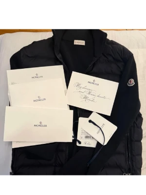 Moncler Tricot Cardigan (M) - Säljer min välvårdade Moncler Tricot Cardigan som jag inte använder längre. Har tröttnat på den och slutat med märkeskläder. Den är självklart äkta, tags, kvitto och allt finns. Storlek: M. Kan även fraktas och tar endast Swish! Kör utanför denna appen! Svart pufferjacka från Moncler med quiltad framsida och stickade ärmar. Jackan har hög krage, dragkedja framtill och två sidofickor med dragkedja. Moncler-logga på vänster ärm. Materialmix av polyester och stickad ull ger en modern look.