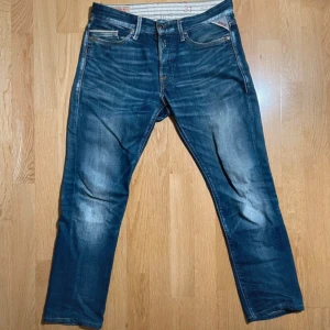 Replay waiton jeans blå tapered 31/30 - Snygga blå jeans från Replay i modellen waiton tapered med klassisk femficksdesign och subtila slitningar. Jeansen har normal passform och är tillverkade i slitstarkt denim med dragkedja och knappstängning. Storleken är W31 och L30. Totala längden på dessa är 90 cm och bredden 40x2 eller 80cm. De är lite mer slimmade längst ner men om du tycker om att ha häng eller en grischig look så är de perfekta!