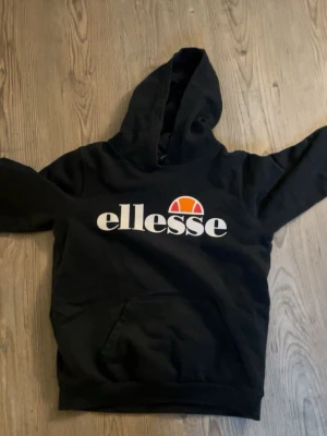 Svart Ellesse hoodie med logga - Säljer en svart hoodie från Ellesse. Klassisk känguruficka framtill och huva. Jätte skön och använd fåtal gånger 💓