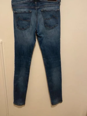 Blå slim fit jeans från Jacob cohen  - Säljer ett par blå slim fit jeans från Jack & Jones med klassisk femficksdesign och normalhög midja. Jeansen har snygg tvättad look och är tillverkade i stretchigt denimtyg för skön passform. Perfekta till en avslappnad stil. Modellen är 157cm. Några trådar är lite av kan skicka bild på det.
