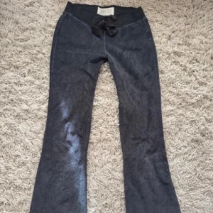 Mörkgrå Hollister byxor - Vintage grå mjukisbyxor från Hollister med utsvängda ben och låg midja med knytband. En bakficka med knappdetalj. Bra skick 