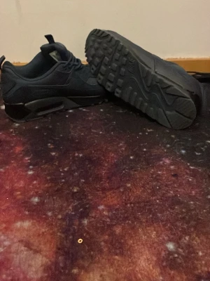 Nike Air Max svarta sneakers - Säljer ett par svarta Nike Air Max sneakers med klassisk luftsula och låg profil. Skorna har en stilren design med diskreta detaljer och är tillverkade i syntetmaterial och textil. Perfekta för dig som gillar sportig och clean streetstyle.