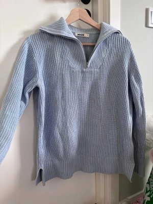 Ljusblå stickad tröja med dragkedja - Säljer en ljusblå stickad tröja från Inesca med halv dragkedja och krage. Tröjan har ribbstickade muddar, slitsar i sidorna och är gjord i ett mjukt, grovt stickat material. Perfekt för lager på lager och chill stil.