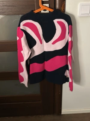 Mönstrad stickad tröja från 365 - Cool stickad tröja från 365 med grafiskt mönster i mörkblått, rosa och vitt. Tröjan har rund halsringning och långa ärmar. Perfekt för dig som gillar färg och vill sticka ut lite extra i höst och vinter.