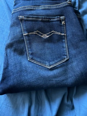 Mörkblå jeans med kontrastsömmar - Snygga mörkblå Repaly jeans med klassisk femficksdesign och vita kontrastsömmar på bakfickan. Jeansen har en rak passform och är tillverkade i denim med en skön känsla. Perfekta för dig som gillar en tidlös och clean look.