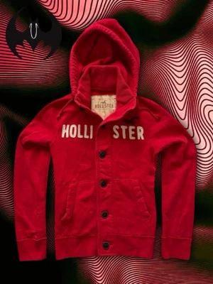 Röd Hollister Kofta  - Röd kofta från Hollister med knappar | Mycket bra skick | Size S | Längd: 62 Bröstvidd: 51cm Armlängd: 68cm | Modell, 178cm 60kg | Går ner i pris vid snabbt köp! | Lägg endast bud med avsikt att köpa, inga fördröjning! | Pris är inte hugget i sten!