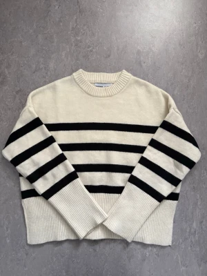 Randig stickad tröja från Bershka - Säljer en krämvit stickad tröja från Bershka med svarta ränder. Endast använd en gång och säljer då den inte kommer till användning. Storlek xs men sitter lite oversized. Tröjan har två slits som sitter vid sidorna av tröjan. 