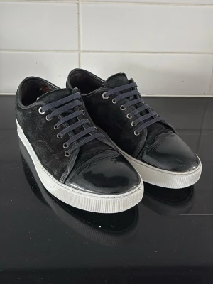 Svarta lanvins - Säljer ett par riktigt schyssta lanvins. Skorna har mörkblå skosnören och vit sula som ger en clean kontrast. Uk 8 vilket motsvarar storlek 42. Hör bara av dig vid någon fråga