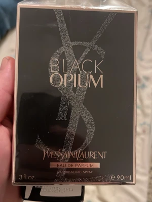 Oöppnad Yves Saint Laurent Black Opium EdP 90ml - Black Opium Eau de Parfum från Yves Saint Laurent är en ikonisk parfym i en elegant svart förpackning med glittrande detaljer och stora YSL-loggan. Doften är djup och sensuell, perfekt för dig som gillar lyxiga och moderna parfymer. Flaskan rymmer 90 ml.
