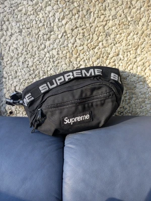 Supreme Waist Bag SS18 Black  - Säljer min autentiska Supreme axelväska köpt från PlugMePlease (Ettresex) i Stockholm för 1850kr. Har använt den mycket genom åren men har mycket liv i sig fortfarande! Ni får bedöma skicket själva, finns inga hål i den överhuvudtaget och det syns att den är "använd." Säljer denna på Vinted också, så först till kvarn gäller. 