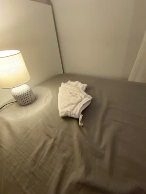 Vita shorts med snörning - Snygga vita shorts med elastisk midja och snörning framtill. Shortsen har fickor på sidorna och är perfekta för varma dagar. Tillverkade i mjukt bomullstyg för maximal komfort.