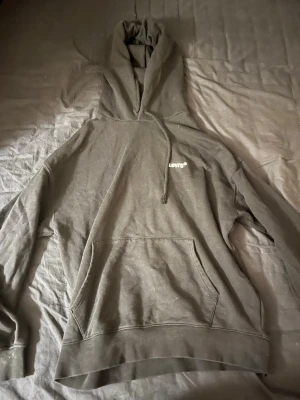Svart hoodie från Levi's - Säljer en svart hoodie från Levi's med liten vit logga på bröstet. Klassisk modell med stor känguruficka framtill, ribbade muddar och justerbar huva. Perfekt för dig som gillar en enkel och stilren look. Pris 300kr men inget pris är spikat!