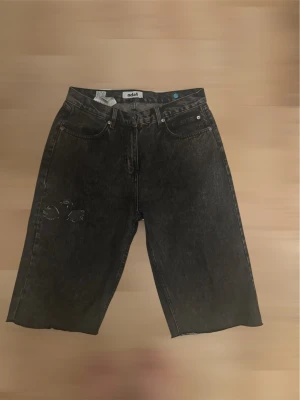 Svarta denimshorts från fsbn - Säljer ett par svarta denimshorts från Noh1 med råa kanter och femficksmodell. Shortsen har en loose passform och klassisk knappgylf. Perfekta för dig som gillar en avslappnad stil. Dom är custom så jag har klippt dom till shorts. 