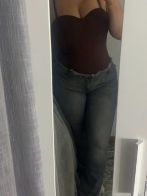 Grå  jeans - Säljer ett par gråa  fit jeans med slitna detaljer vid midjan. Jeansen har klassisk femficksdesign och normalhög midja. Perfekta för en avslappnad och trendig look.