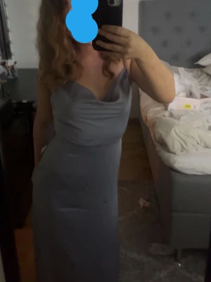 Ljuslila långklänning med slits - Elegant ljuslila långklänning med smala axelband och draperad urringning. Klänningen har en figurnära passform och en hög slits på sidan som ger en snygg siluett. Perfekt för speciella tillfällen och studentfirande. (Bilden i mitten är det regn droppar ej smuts)