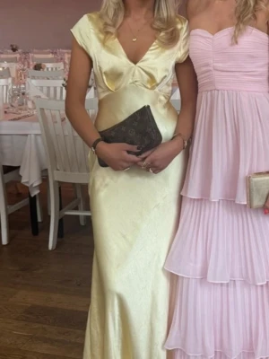 Ljusgul långklänning med v-ringning - Gul super fin satinklänning, aldrig andvänd och prislappen är kvar! Säljer den pga jag valde en annan balklänning obs bilden är lånad men skriv så skickar jag fler