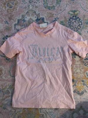 Rosa Juicy Couture t-shirt - Säljer en ljusrosa t-shirt från Juicy Couture i bomull. T-shirten har korta ärmar och texten 'Juicy' 