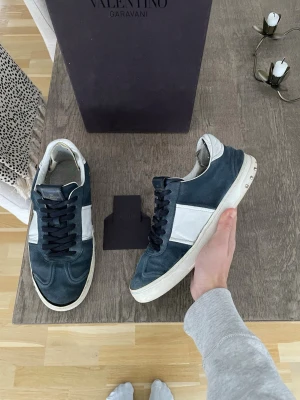 Navy Valentino Flycrews  - Säljer dessa navy Valentino Flycrews i storlek 42🔥De har 17/22 nitar kvar och de kommer med box+valentino kort. Allt är äkta och skorna har defekter som syns på bild då sulan kan behövas limmas lite där fram på ena skon, de är fixade lite inuti och saknar sula inuti skon samt en liten defekt under skon som syns på bild med👍