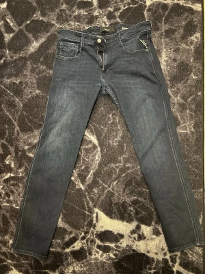 Mörkblå slim fit jeans från Replay - Snygga mörkblå slim fit jeans från Replay med klassisk femficksdesign och diskreta kontrastsömmar. Jeansen har dragkedja och knapp i midjan samt en liten logotypdetalj vid fickan. Perfekta för en trendig och avslappnad look. Storlek 33! Blivit lite trånga på mig, 177 76kg. Inga slitningar, kom med bud💯Var inte rädd att ställa frågor! Svarar så fort jag kan😊
