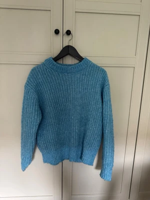 Blå stickad tröja från 157 - Mysig blå stickad tröja från 157 i storlek XS. Tröjan har en grovstickad struktur, rund halsringning och långa ärmar. Den är oversized.