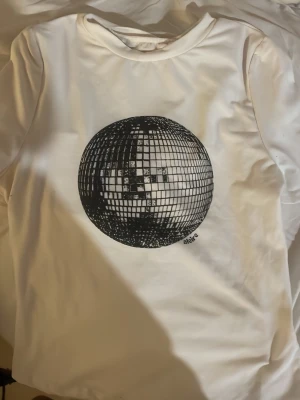 Vit t-shirt med discokula-tryck - Snygg vit t-shirt  med ett stort svart discokula-tryck på bröstet. Använt 1 gång. Frågor/pris kan diskuteras 😇