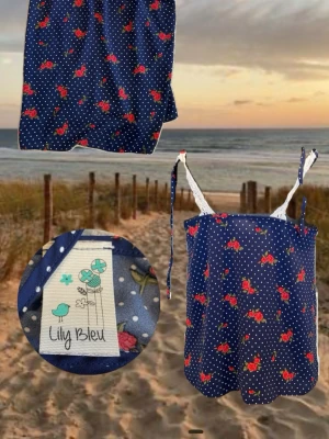 Blå blommig topp från Lily Bleu - Söt blå topp med vita prickar och små röda blommor från Lily Bleu. Topp med tunna axelband som knyts och spetsdetaljer vid axlarna. Perfekt för varma dagar och enkel att matcha med jeans eller shorts.