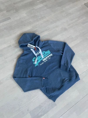 Superdry hoodie herr blå - Den är liten i storleken så L är mer som M/S. Den är helt ny och aldrig använd. 