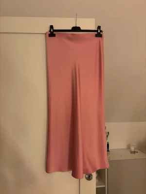 Rosa satinkjol  - Säljer en snygg långkjol i satin från Zara i storlek xs med en mjuk rosa färg. Kjolen har en rak och enkel design som faller fint längs benen. Går ungefär ner till anklarna på mig som är 165 cm lång❣️
