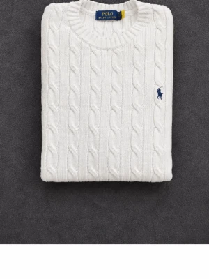 Vit kabelstickad tröja Polo Ralph Lauren - Vit kabelstickad tröja från Polo Ralph Lauren med rund halsringning och klassisk blå broderad logga på bröstet. Tröjan har ett tidlöst mönster och ribbade muddar. Perfekt för dig som gillar stilren och klassisk design. Medföljer original tags. Har ingen stress med att sälja så inga skambud.