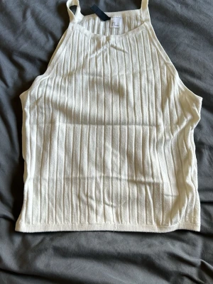 Vit ribbad linnetopp från HM - Snygg vit ribbad linnetopp från Gina Tricot med smala axelband och rak passform. Perfekt till jeans eller kjol för en fräsch look. Materialet är mjukt och stretchigt för extra komfort.