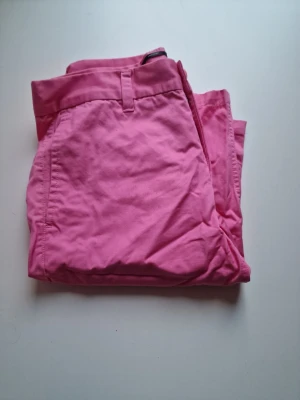 Rosa chinoshorts  - Fräscha rosa shorts i mjuk bomull med klassisk passform och sidfickor. Perfekta för varma dagar när du vill ha en färgklick i din outfit. Stilrena och enkla att matcha med t-shirt eller linne.