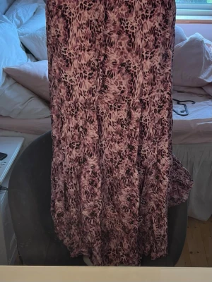 Långkjol  - Långkjol i rosa/lila med ett super fint mönster! Kjolen har resår i midjan och passar därför flera storlekar! Köpt på marknad så finns ingen storlek men skulle säga att det är som en M men passar även S och L eftersom den är väldigt stretchig🌸