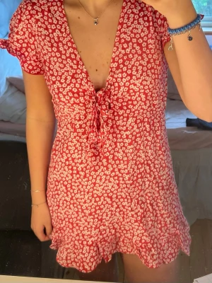 Röd blommig kortklänning - Supersöt röd kortklänning med blommönster! Super söt och har använts 1 gång så är i jätte bra skick!🌸
