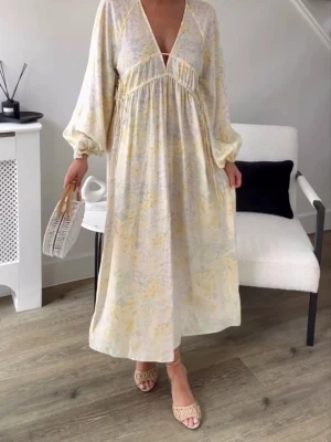 Oversized klänning med knytdetalj, stl 38 - En oversized, vadlång klänning i vävd kvalitet med djup V-ringning och smala dragskor under bysten som knyts i sidorna. Lång, raglanskuren ballongärm med smal resår vid ärmslut. Perfekt för sommarens varma dagar och har en romantisk vibe. Från H&M i stl 38. Slutsåld!