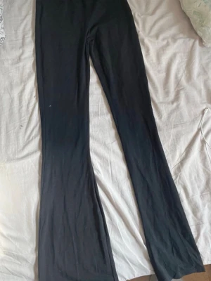 Svarta utsvängda leggings - Säljer ett par svarta leggings med utsvängda ben. De är höga i midjan och har en tight passform upptill som blir vidare nedtill. Perfekta till en chill outfit eller när du vill ha något bekvämt men ändå snyggt. Materialet känns mjukt och stretchigt.