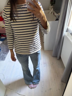 Randig trekvarts topp - En fin trekvarts topp i vit och marinblå randig design. Tillverkad i mjuk bomull med rund halsringning och normal passform. Perfekt för en avslappnad och stilren look. Bara fråga ifall du undrar något!